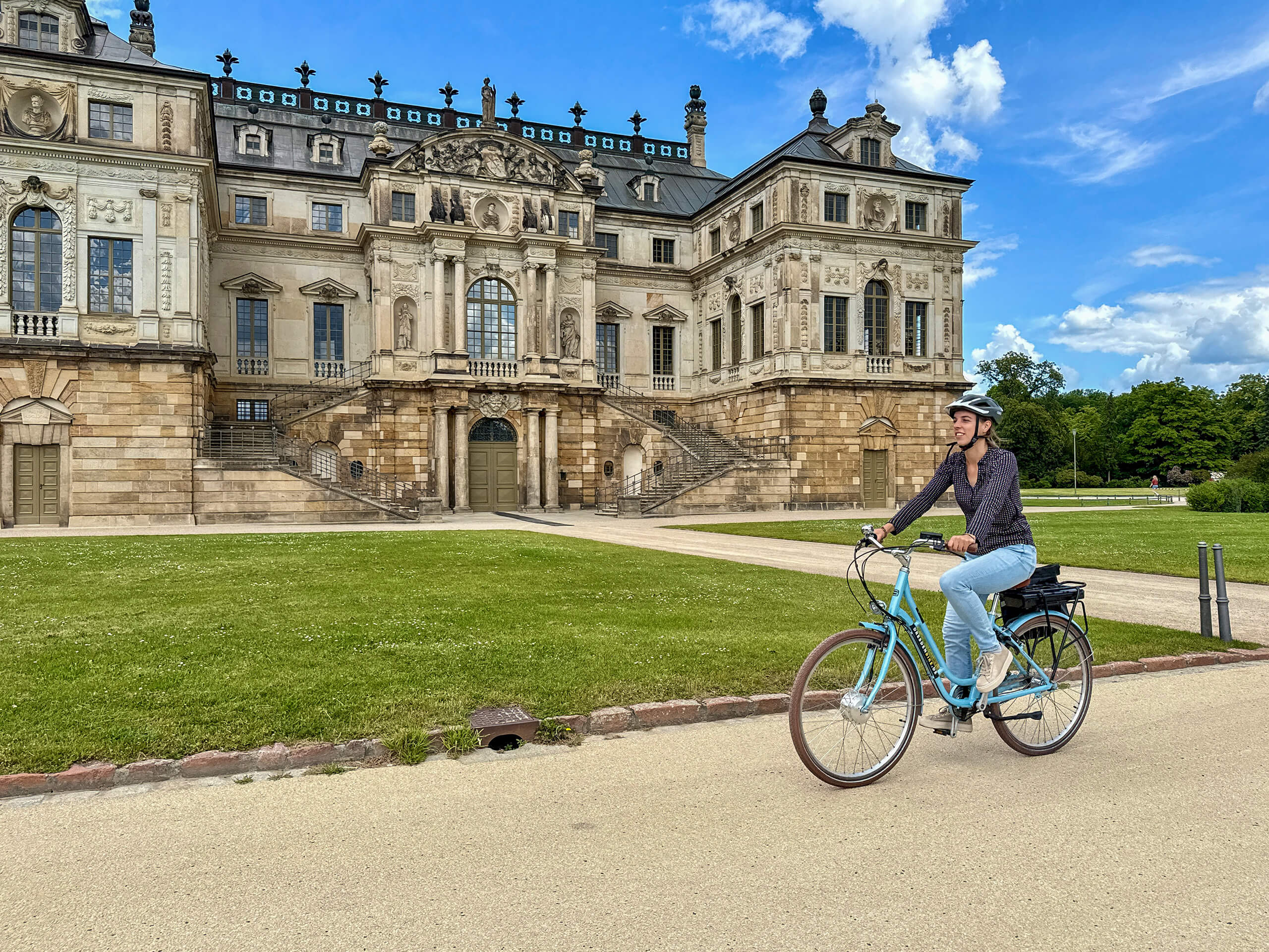 Radfahrerin auf einem Leihfahrrrad von Dresden Bike vor dem Palais im Großen Garten